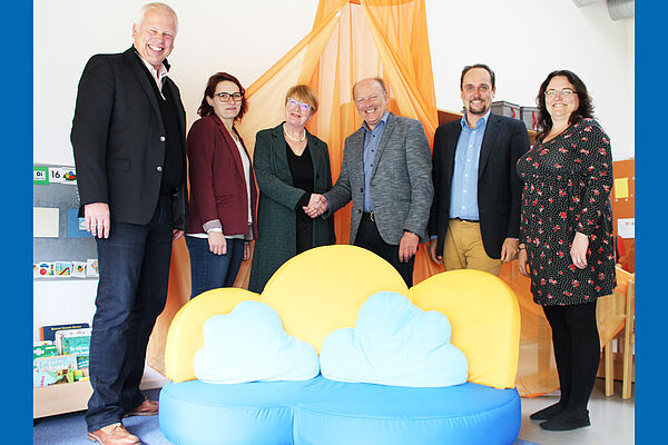 Vertreter der Lebenshilfe und der Firma omagaconsulting stehen hinter einer Couch für Kinder mit wolkenförmigen Kissen